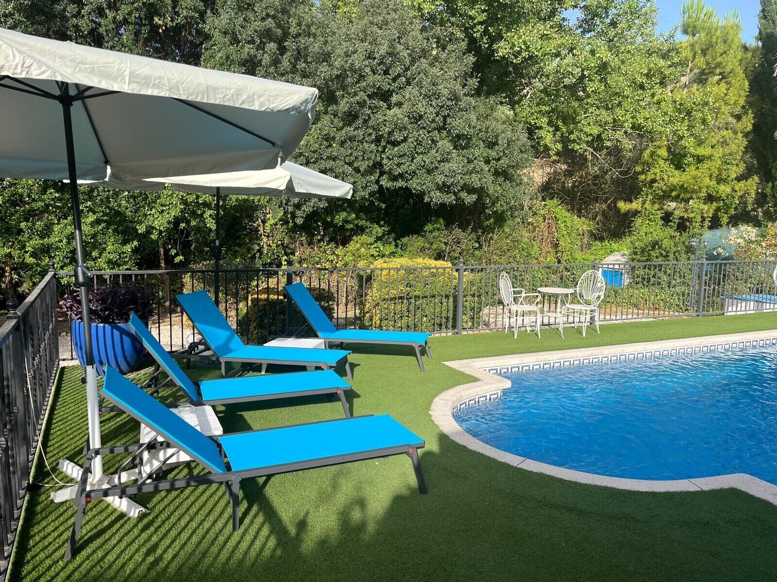 A swimming pool with blue lounge chairs and a white umbrella.