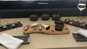 Una mesa de comedor elegantemente dispuesta con diversos alimentos, utensilios y una copa de vino.