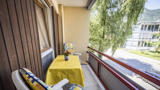 A balcony with a yellow table, a chair, and a potted plant. - Apartment Sophia, 60sqm, 1 bedroom, balcony with mountain view (Bad Reichenhall)