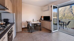 Eine moderne Küche mit Essbereich, einem Fernseher und einem Balkon mit Blick auf die Berge.