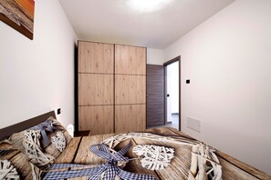 Une chambre à coucher comprenant un lit, une armoire et une porte donnant sur une autre pièce.