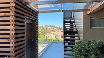 Un bâtiment moderne avec une façade en bois, une porte en verre et un escalier en métal menant à un balcon.