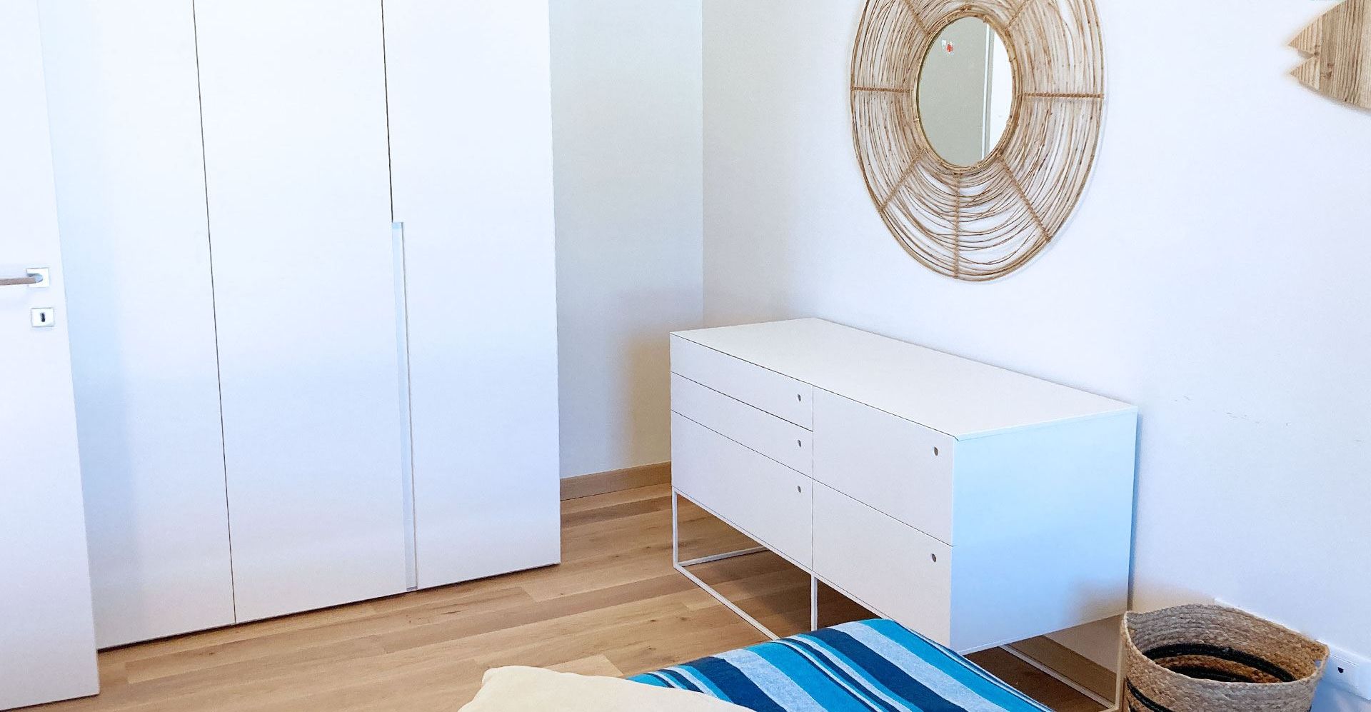 Ein Schlafzimmer mit Kleiderschrank, Nachttisch, Spiegel und Bett.