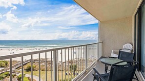 A balcony with a view of the beach, a table, chairs, and a railing. - Seaside Beach & Racquet 4608 Views & Chill Hues (Orange Beach)