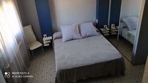 A hotel room with a large bed, a bedside table, a chair, a mirror, and a patterned floor. - Casa Totalmente Nueva, Para 16 Personas a 12 km de Burgos en un Pueblo Tranquilo (Villanueva-Matamala)