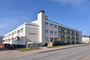 A modern multi-story building with a flat roof, a prominent entrance with steps, and a nameplate on the facade. - At Undine Beach, Germany (Sylt)