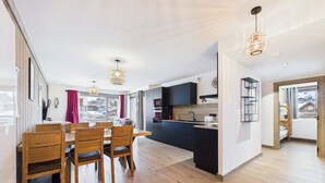A modern kitchen with dark cabinets, a central island, and pendant lighting. - Cozy apartment in the heart of the village with terrace and garage - Les Gets (Les Gets)