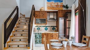 Une cuisine avec des meubles de rangement en bois, un réfrigérateur en acier inoxydable et une table à manger pour deux personnes.