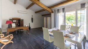 A dining area with a wooden ceiling, a dining table set for four, and a view of the outdoors through large windows. - "l'escapade"... Entre Lacs, mer et Montagnes (Hérépian)