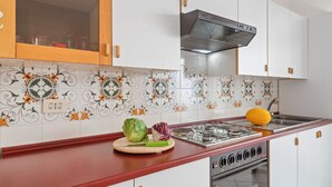 A kitchen with white cabinets, a red countertop, a stove, and a decorative backsplash. - GuestHost - Comfortable 50 sqm apartment with terrace, able to accommodate up to 4 people, located on the fifth floor of a building with lift (NOT suitable for disabled people - 15 steps to access it). The property is located in a quiet area of ​​Tao (Taormina)