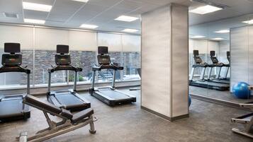 A gym with treadmills, a rowing machine, and a blue exercise ball.