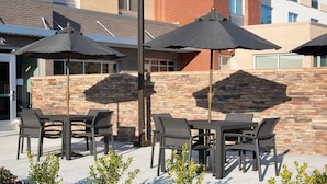 An outdoor patio with tables and chairs, umbrellas, and a stone wall. - Fairfield Inn & Suites by Marriott Memphis Arlington (Arlington)
