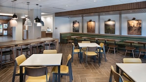 A restaurant with booths, tables, and chairs, featuring a wooden floor and pendant lighting. - Fairfield Inn & Suites by Marriott Memphis Arlington (Arlington)
