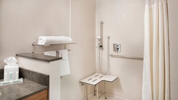 Et moderne badeværelse med bruser, et vaskeskab med håndklædestang og et lille bord med toiletartikler.