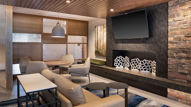A modern living room with a fireplace, comfortable seating, a flat-screen TV, and a wooden ceiling. - Fairfield Inn & Suites by Marriott Memphis Arlington (Arlington)