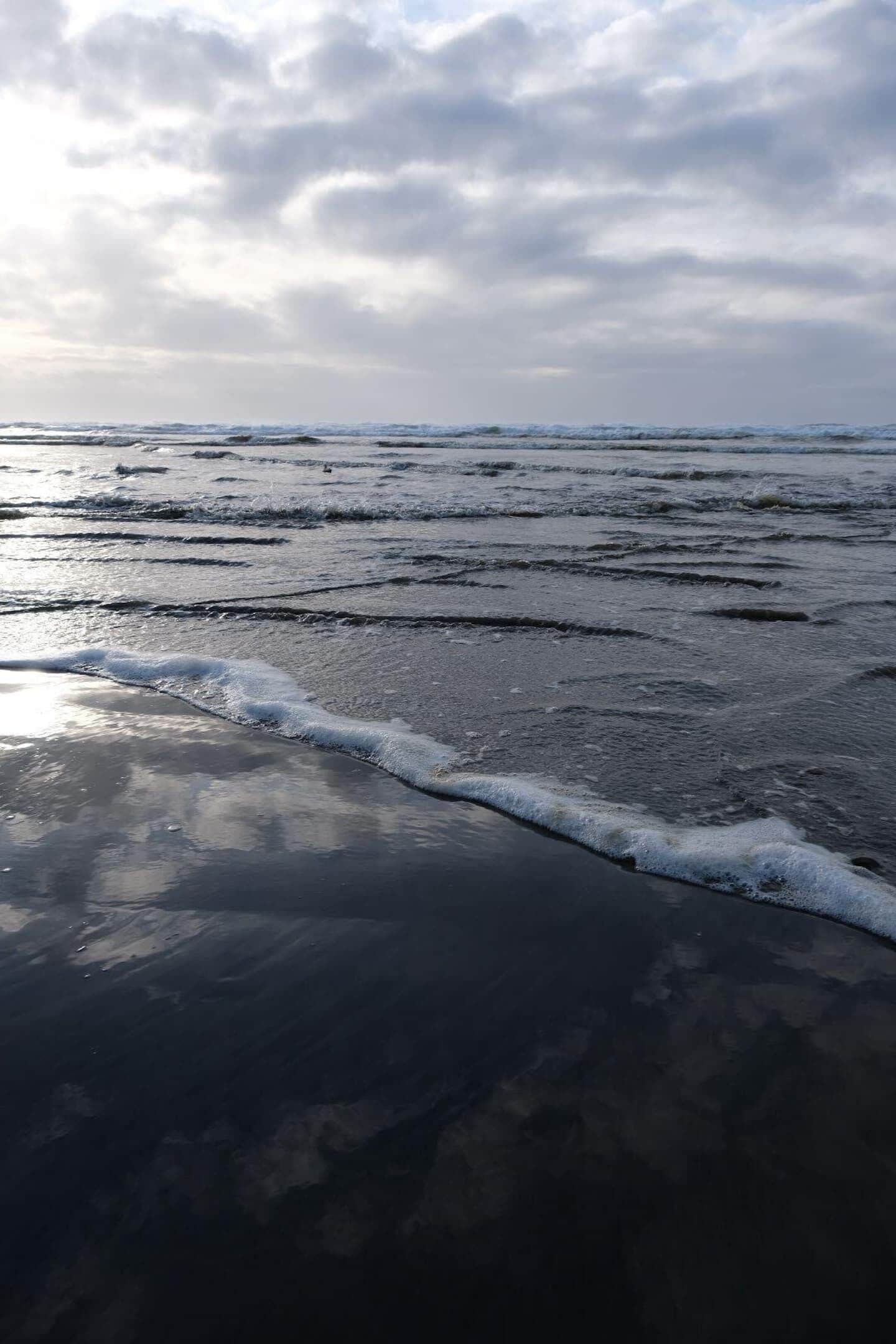 Une plage avec des vagues et un ciel nuageux.