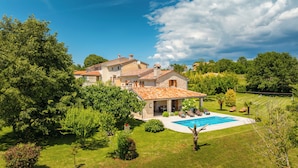 Eine Villa mit Swimmingpool, umgeben von üppigem Grün und Bäumen.