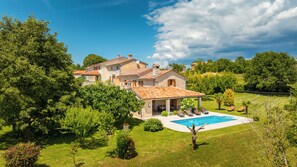 Eine Villa mit Swimmingpool, umgeben von üppigem Grün und Bäumen.