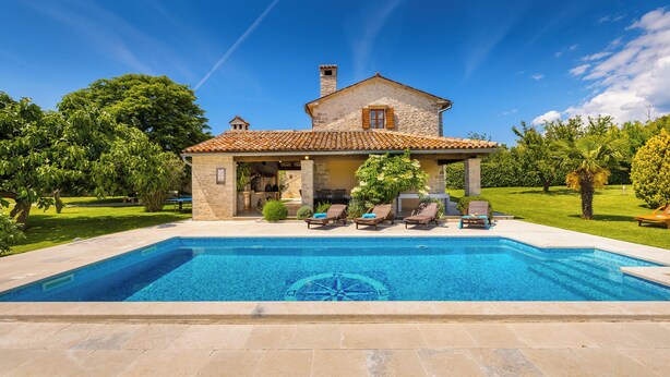 Ein Haus mit Schwimmbad, Liegestühlen und einem Garten.