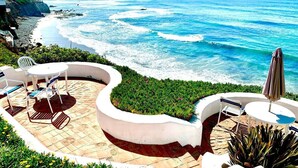 A patio with outdoor seating and a view of the ocean.