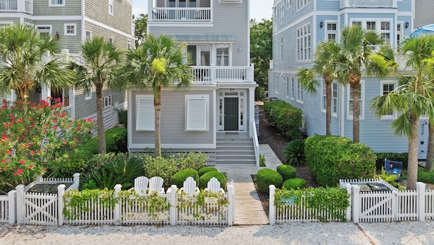 A coastal residential area with a two-story house featuring a front porch, a balcony, and a small deck. - Satilla Cottage - 4 Bedrooms in Coast Cottages (Saint Simons Island)