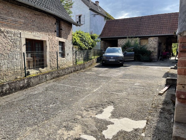 A gravel driveway leading to a building with a stone facade and a parked car. - The Seasons in the Heart of the Vineyard! Cozy House in Magical Alsace 🍀 (Cleebourg)