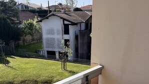 A balcony with a table and chairs, a small garden view, and a building in the background. - T1 on the shores of Lake Christus in Saint Paul Les Dax (Saint-Paul-lès-Dax)