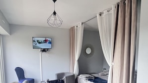 A modern hotel room with a bed, a TV mounted on the wall, a dining table, and a chair. - T1 on the shores of Lake Christus in Saint Paul Les Dax (Saint-Paul-lès-Dax)