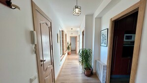 A hallway with wooden flooring, a potted plant, and a hanging light fixture.