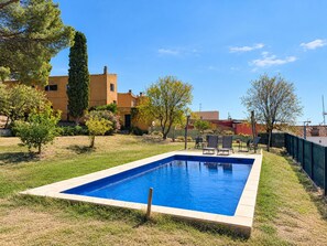 A rectangular swimming pool with a tiled edge, surrounded by grass and trees.