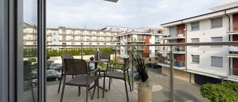 A balcony with chairs and a table, overlooking a residential area with multiple apartment buildings.