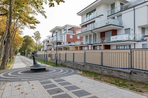 Un edificio residencial moderno con varios balcones, un sendero ajardinado y un elemento circular central.
