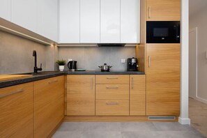 Una cocina moderna con armarios de madera, encimera negra, microondas y cafetera.