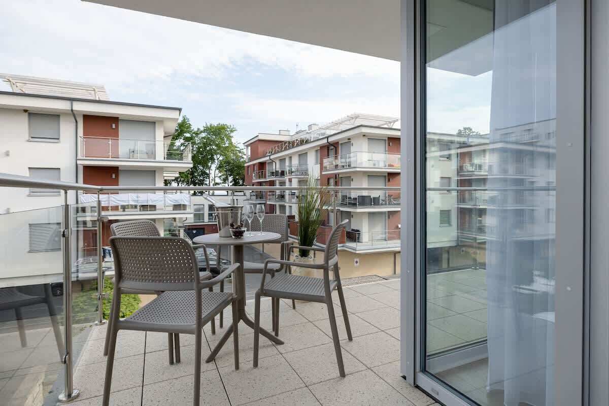 Ein Balkon mit Gartenmöbeln und einer Glastür, die in einen Wohnbereich führt.