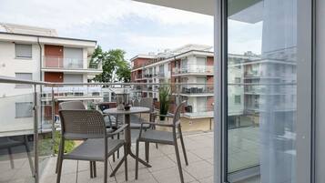 Ein Balkon mit Gartenmöbeln und einer Glastür, die in einen Wohnbereich führt.