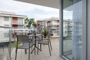 Un balcón con mobiliario exterior y un ventanal de vidrio que da a una zona residencial.