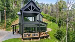 A modern two-story cabin with a deck, surrounded by forest. - Pet-Friendly w/ Deck, Views + Biltmore Pass | Modern Maggie Valley Escape (Waynesville)