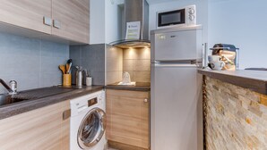 A compact kitchen with a washing machine, a refrigerator, and a microwave. - SUEDE 2 AP4208 By Riviera Holiday Homes (Niza)