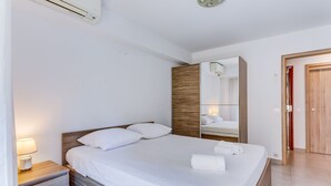A hotel room with a bed, bedside lamp, wooden headboard, and a mirror. - SUEDE 2 AP4208 By Riviera Holiday Homes (Niza)