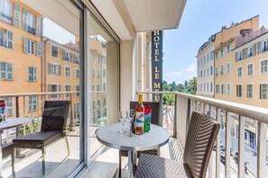 Een balkon met een tafel, stoelen, een fles wijn en een wijnglas.