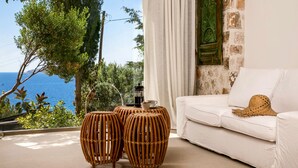 A room with a white sofa, a woven coffee table, and a view of the sea. - Kale Suites (Kas)