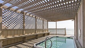 En træterrasse med pool, bænke og havudsigt.