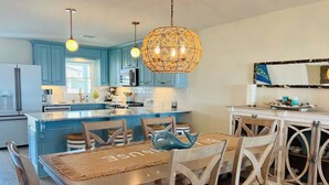 Uma cozinha moderna com armários azuis, uma ilha central, luminárias pendentes e um globo decorativo.