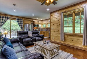 A log cabin interior with a living room, dining area, and kitchen.