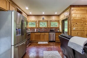A kitchen with wooden walls, a refrigerator, a dishwasher, and a window.