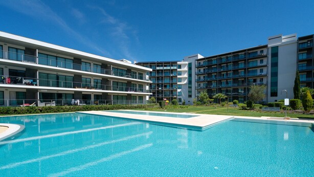 Un hôtel moderne doté d’une grande piscine, de nombreux balcons et d’un jardin bien entretenu.