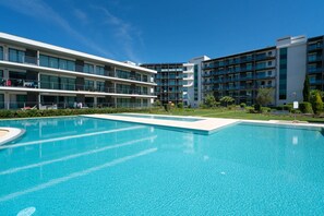 Un hotel modern amb una gran piscina, múltiples balcons i una zona de jardí ben cuidada.