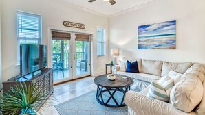 A living room with a TV, a sofa, a coffee table, and a ceiling fan.