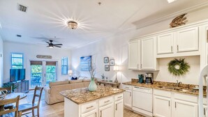 A spacious kitchen with white cabinets, a granite countertop, and a ceiling fan.