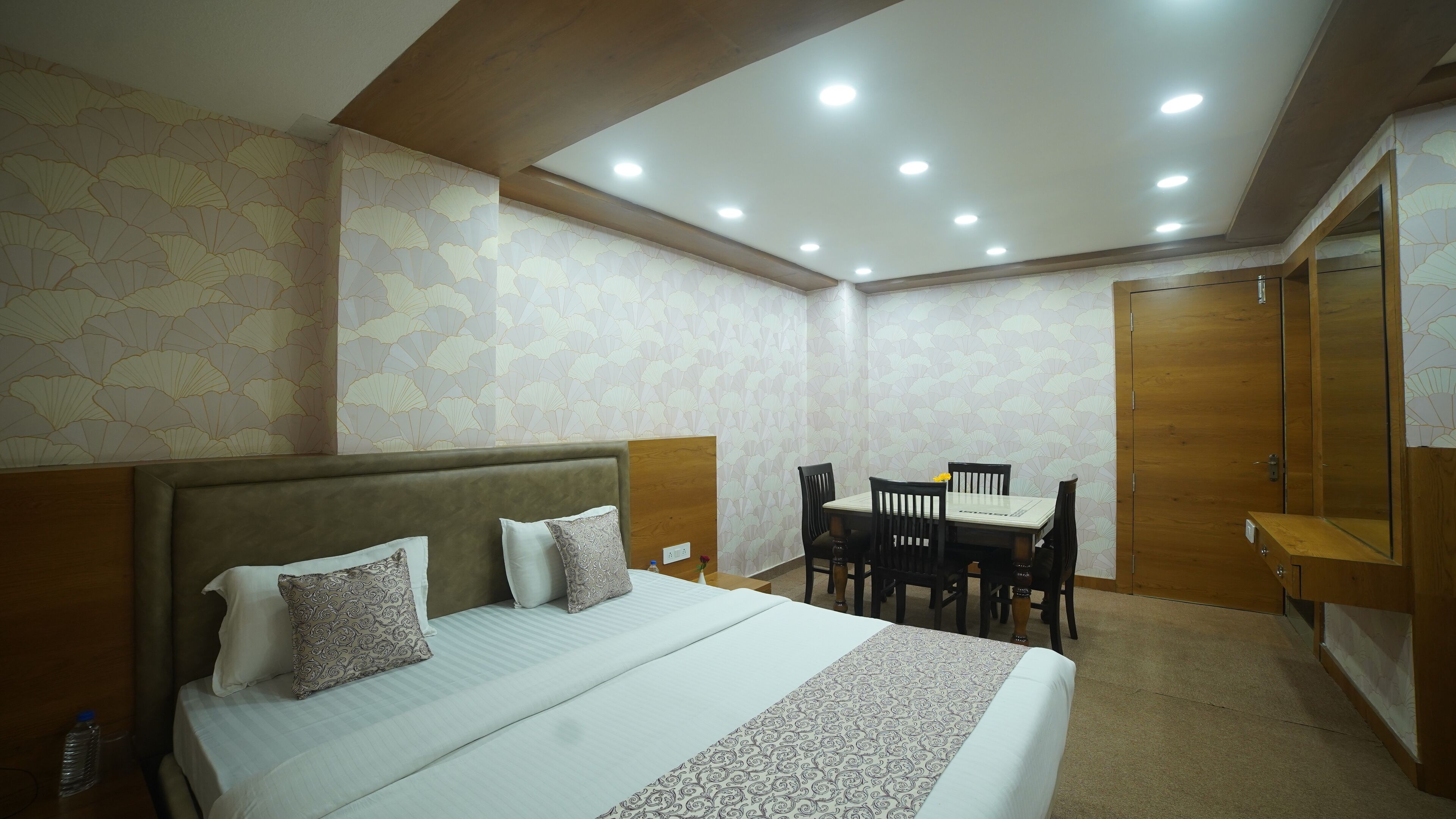 Una habitación de hotel con cama, una mesa de comedor con sillas y un armario.